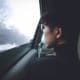 a woman with glasses sitting in a car looking out the window.