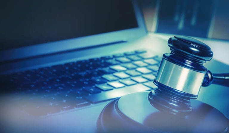 Judge's gavel sitting next to a laptop.