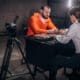 a man and a woman sitting at a table in front of a camera.