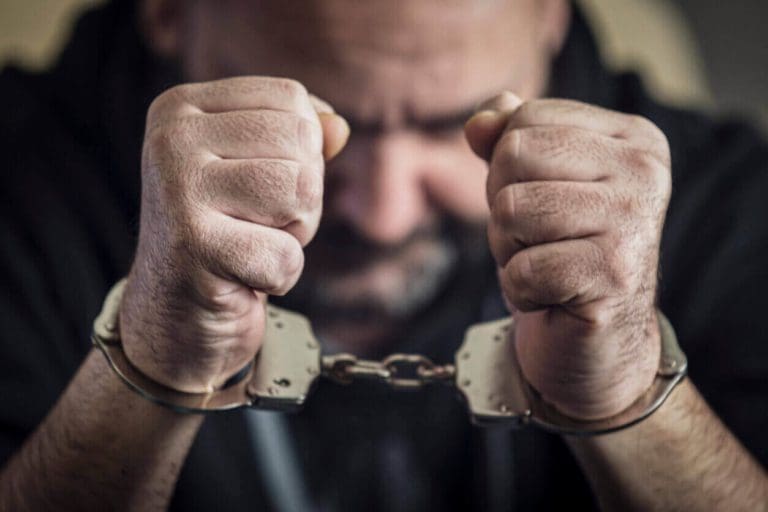 a man holding two handcuffs in his hands.