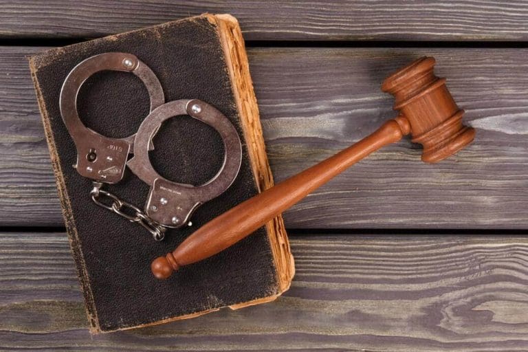 a judge's gaven and a pair of handcuffs on top of a book.