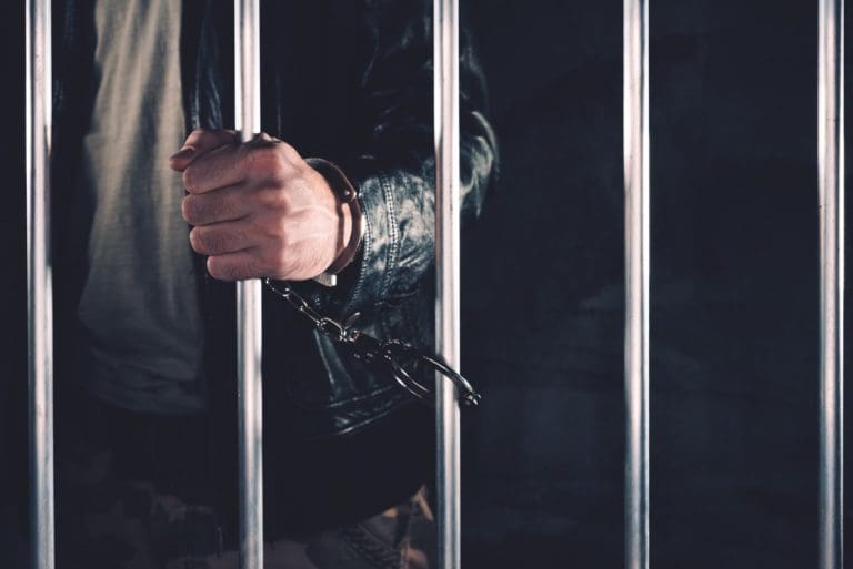 a man in a leather jacket is holding a metal bar.