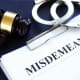 a gavel and handcuffs with the word misdemeanor.