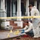 two men in protective suits working on a crime scene.
