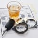 A pair of handcuffs, a glass of alcohol and a car key.