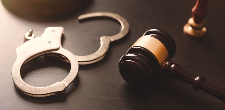 Handcuffs and a gavel on a table.