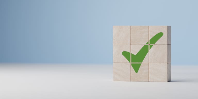 A wooden block with a green check mark on it.