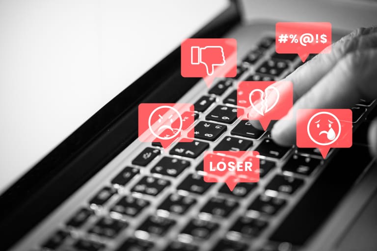 A person typing on a laptop with social icons on it.